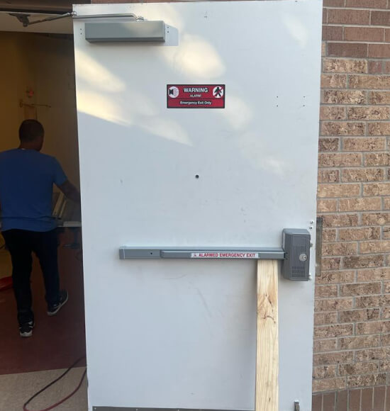 panic-bar-exit-device-installation-dallas-img Commercial locksmith installing panic bar exit device in Dallas, TX