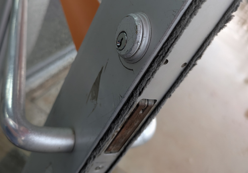 Existing lock cylinder on an aluminum storefront entrance door